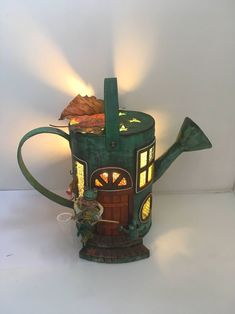 a green teapot shaped like a house with a light coming out of it's door