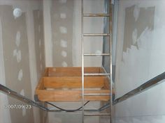 a ladder is attached to the side of a wall in a room with drywall