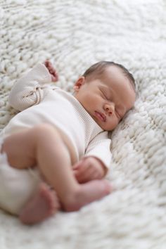 a baby laying on top of a white blanket