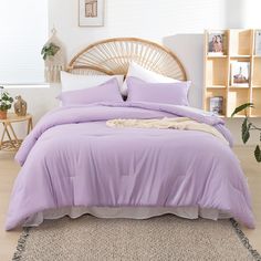 a bed with purple sheets and pillows in a room