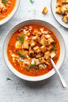 two bowls of tomato soup with tofu croutons and parsley on the side