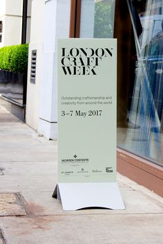 a sign is on the sidewalk in front of a building that says london city week