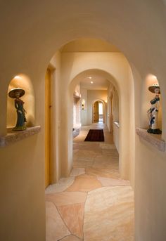 an archway leading to a hallway with statues on the wall and lights on either side