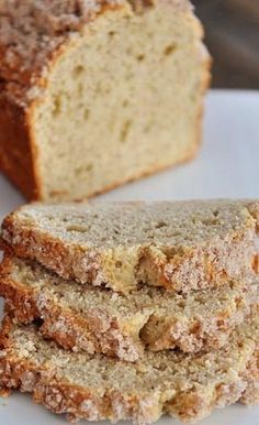 sliced loaf of bread sitting on top of a white plate next to a butter knife