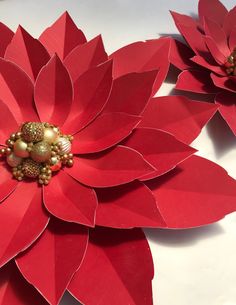 three red paper flowers with gold beads on them