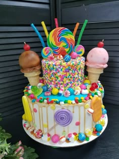 a multi layer cake decorated with candy, lollipops, and ice cream