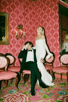 a bride and groom pose for a wedding photo in an ornate room with pink walls