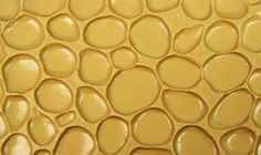 a close up view of the surface of a yellow tile with circles and dots on it