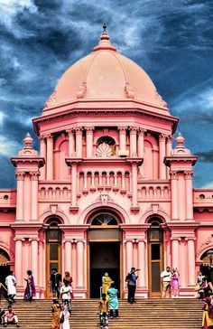 people are walking up and down the steps in front of a pink building