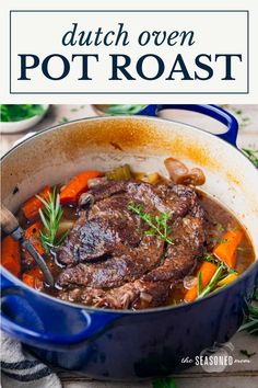 dutch oven pot roast with carrots and mushrooms in a blue skillet on a wooden table