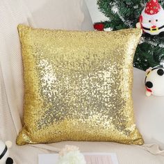 a gold sequin pillow sitting on top of a couch next to a christmas tree