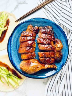 sliced chicken on a blue plate with chopsticks next to it and another dish in the background