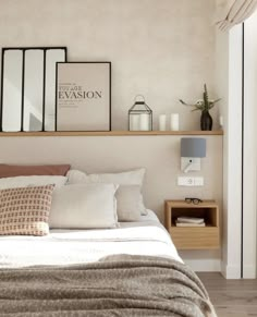 a bed with white sheets and pillows in a bedroom next to a shelf filled with pictures