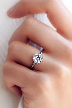 a woman's hand with a diamond ring on her finger