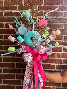 a hand holding a bouquet made out of candy and candies on a brick wall