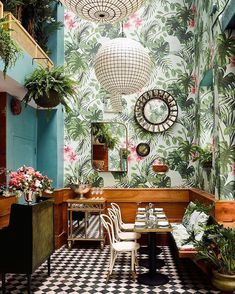 the interior of a restaurant decorated with tropical wallpaper and potted plants on the walls