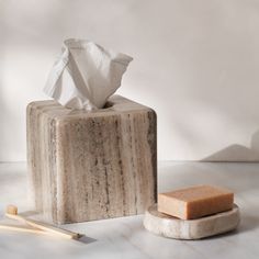 a marble tissue dispenser next to two bamboo sticks