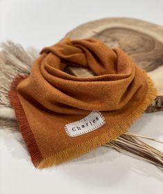 an orange scarf on top of a piece of wood with a tag that says charlotte