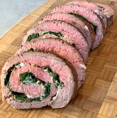 sliced meat with spinach and cheese on a cutting board