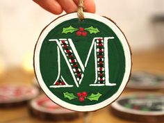 a hand holding a christmas ornament with the letter m on it