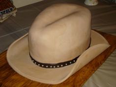 a white cowboy hat sitting on top of a wooden cutting board next to a bag