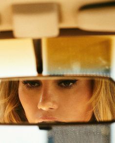 a woman's face is reflected in the rear view mirror as she sits down