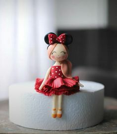 a little doll sitting on top of a toilet paper roll with a red dress and polka dot bow