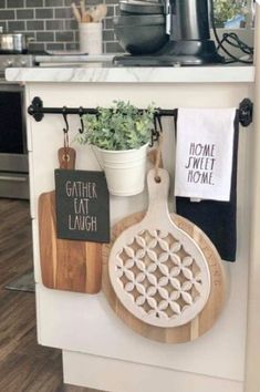 kitchen utensils hanging on the wall next to a potted plant and cutting board