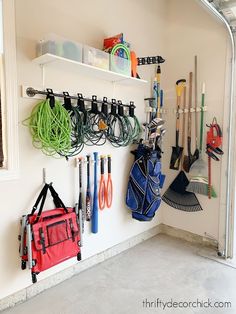 there are many different items hanging on the wall in this garage, including golf clubs and other sports equipment