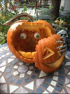 two carved pumpkins sitting on top of a table with eyes and hands in them