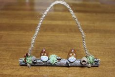 three little gnomes are sitting on a log with rope hanging from the ends,