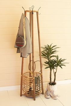 a coat rack and potted plant in front of a wall