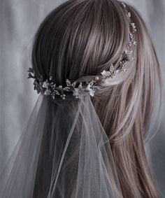 the back of a woman's head wearing a veil with flowers and leaves on it