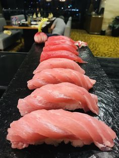 several pieces of sushi are lined up on a black table in the middle of a room