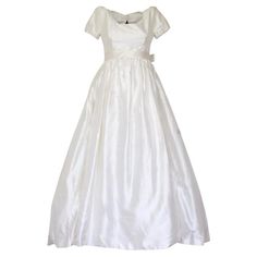 a white dress with short sleeves and a bow at the waist, on a mannequin