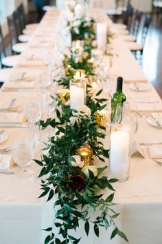 a long table with candles and greenery is set up for a formal dinner party