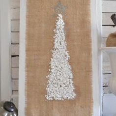 a burlap christmas tree is hanging on the wall next to a candle holder