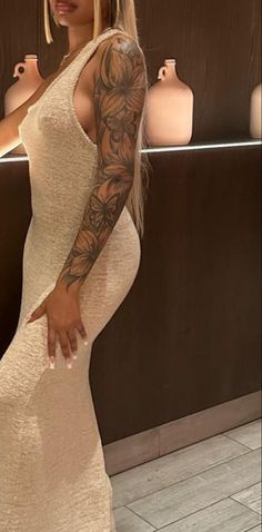 a woman in a white dress with tattoos on her arm and arms, posing for the camera