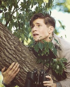 a man holding onto a tree with binoculars