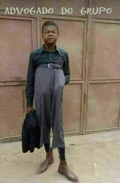 a young boy standing in front of a garage door with his hand on his hip