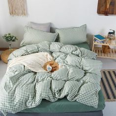 an unmade bed with green and white checkered comforter, pillows and blankets