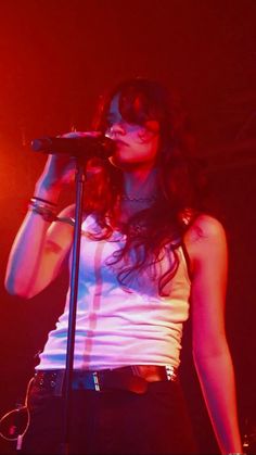 a woman singing into a microphone in front of a red and blue light at a concert