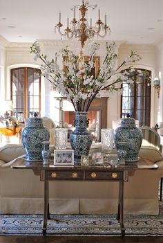 a table with vases and pictures on it in a room filled with couches