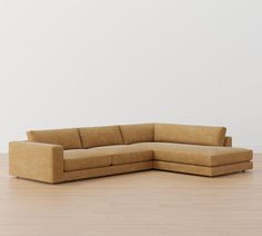 a tan couch sitting on top of a hard wood floor next to a white wall