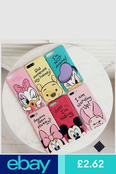 four phone cases with cartoon characters on them sitting on top of a white table in front of a window