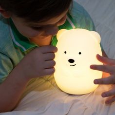 a young boy is playing with a light that looks like a polar bear on the bed