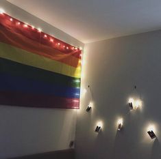 there are several lights on the wall in this room with a rainbow flag hanging above it