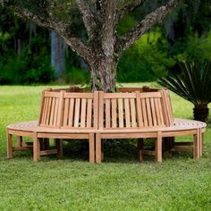 a wooden bench sitting under a tree in the grass