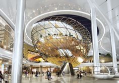 people are walking around in the lobby of an indoor shopping center with large glass and metal structures