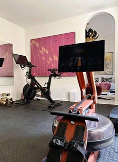 there is a bike and exercise equipment in the room with pink paintings on the wall